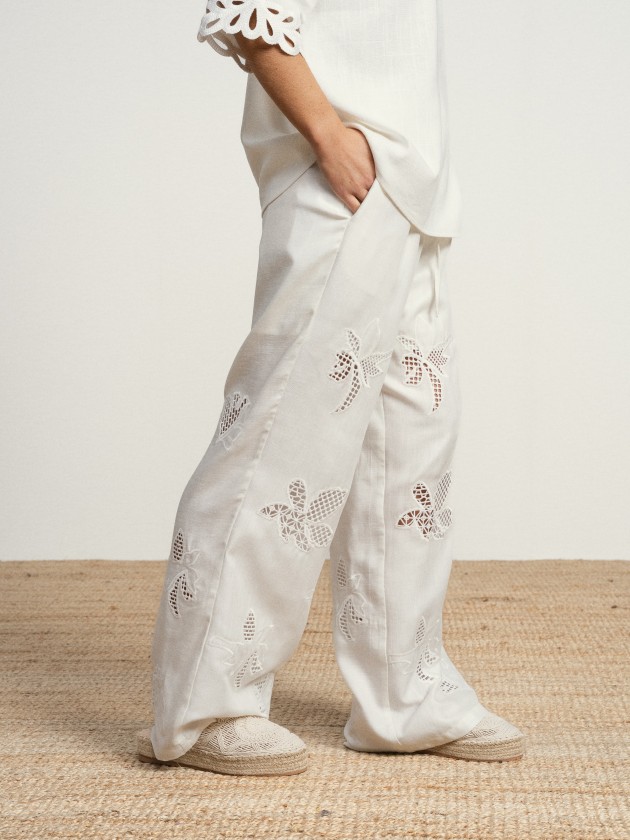 Wide-leg linen trousers with floral embroidery.